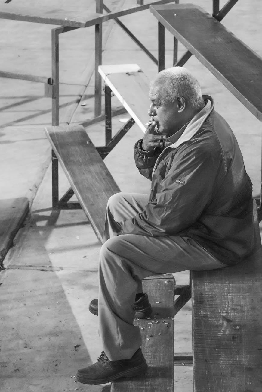 pensive man smoking on bleachers in black and white