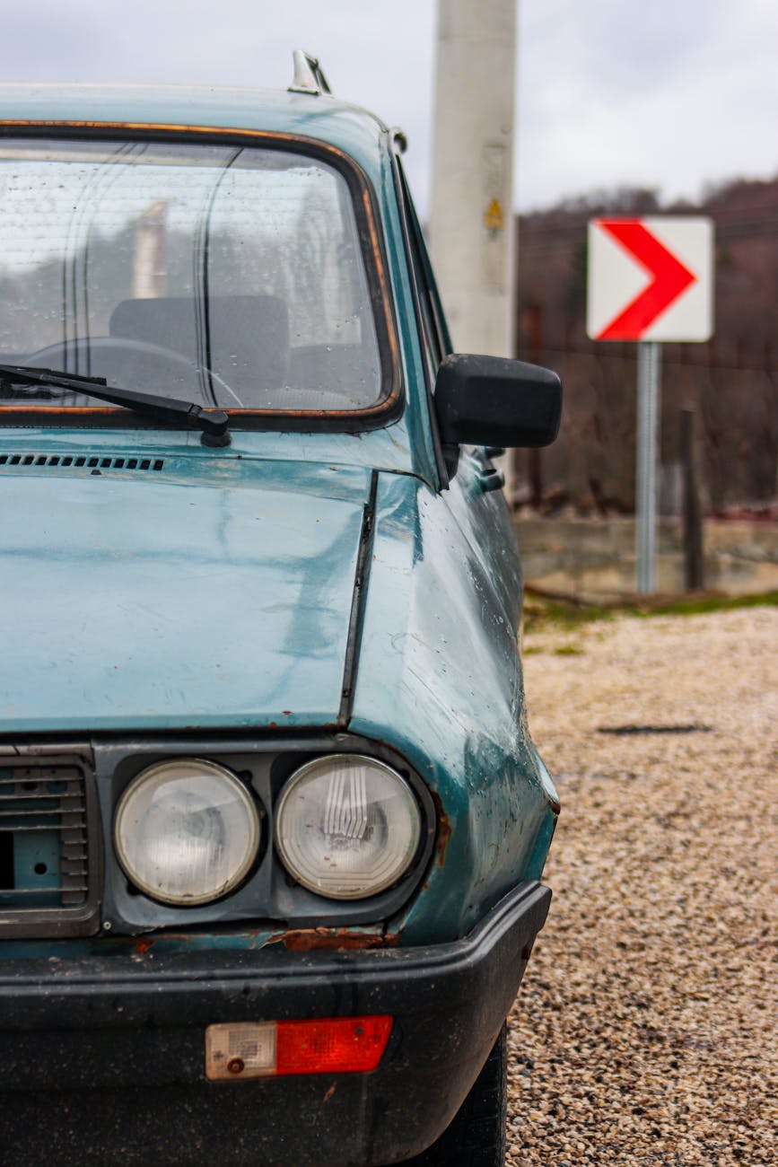 vintage car by roadside with weathered sign