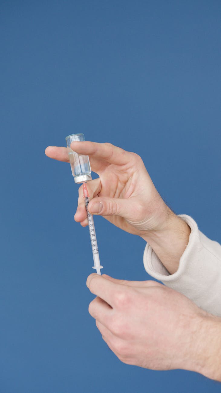 a person holding a vial and a syringe