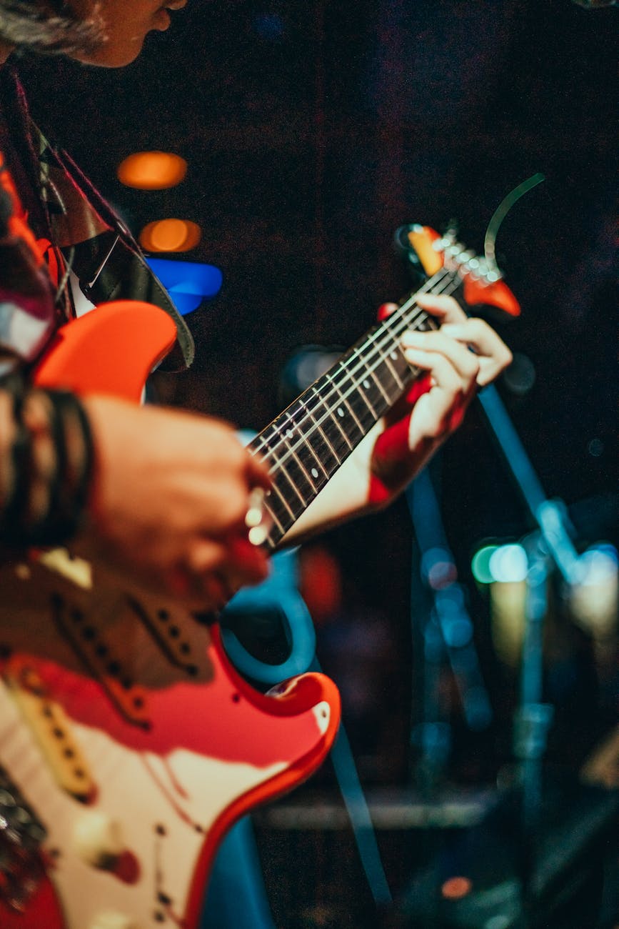person playing red electric guitar